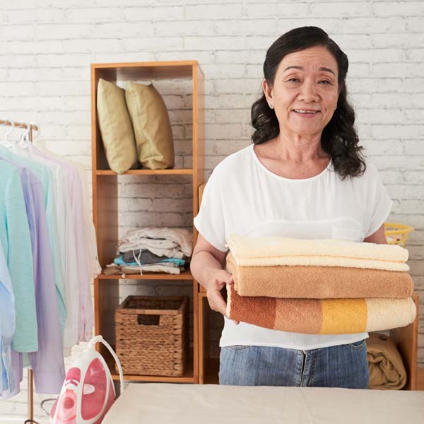 A woman holding some towels in a residence. She's smiling.